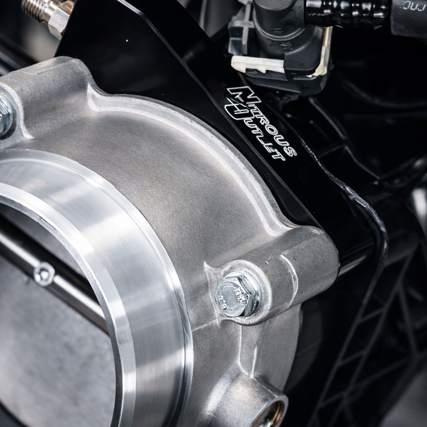 Close-up of a metallic engine component with Nitrous Outlet branding.