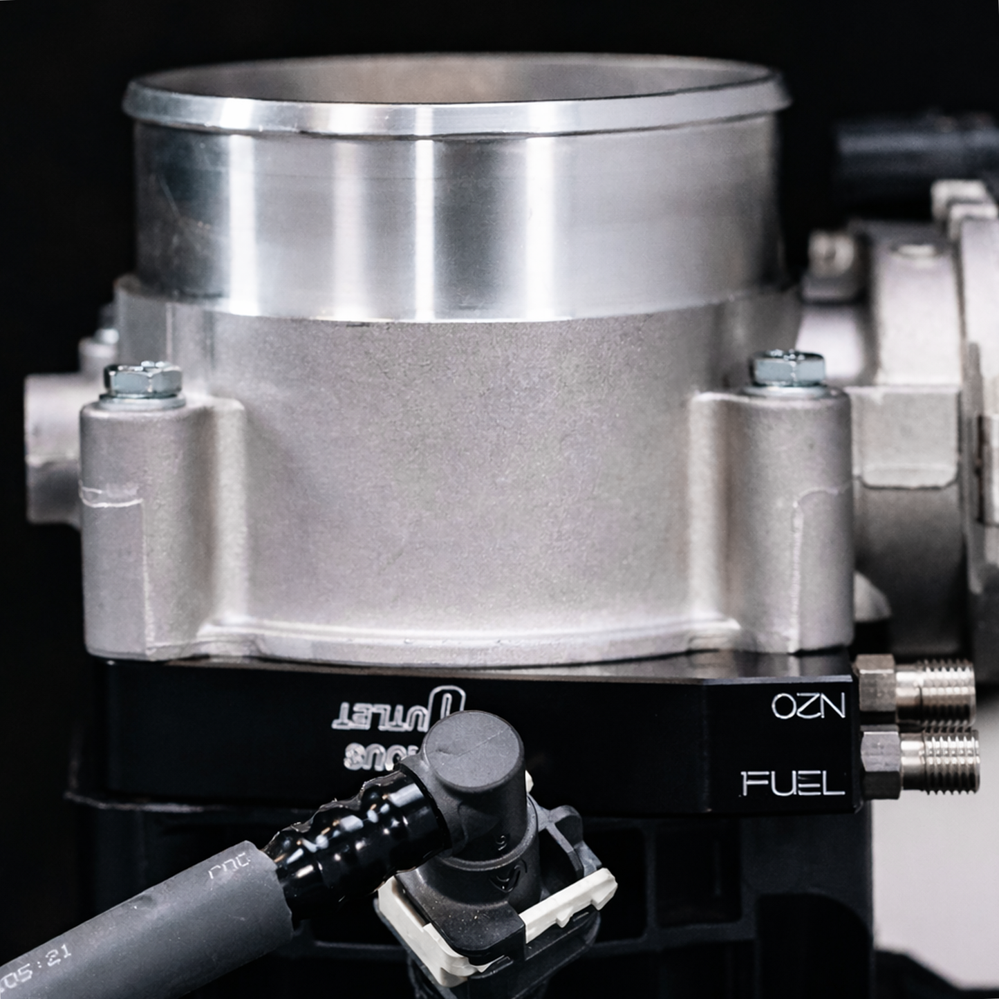 Close-up of a fuel injection system with 'OZ' branding on a black background