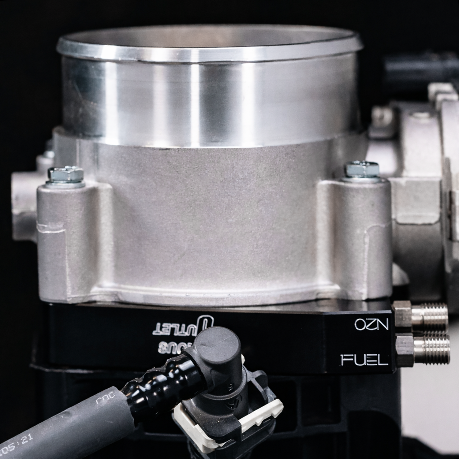 Close-up of a fuel injection system with 'OZ' branding on a black background